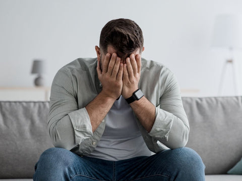 Exhausted man holding his face overwhelmed by mental fatigue and brain fog